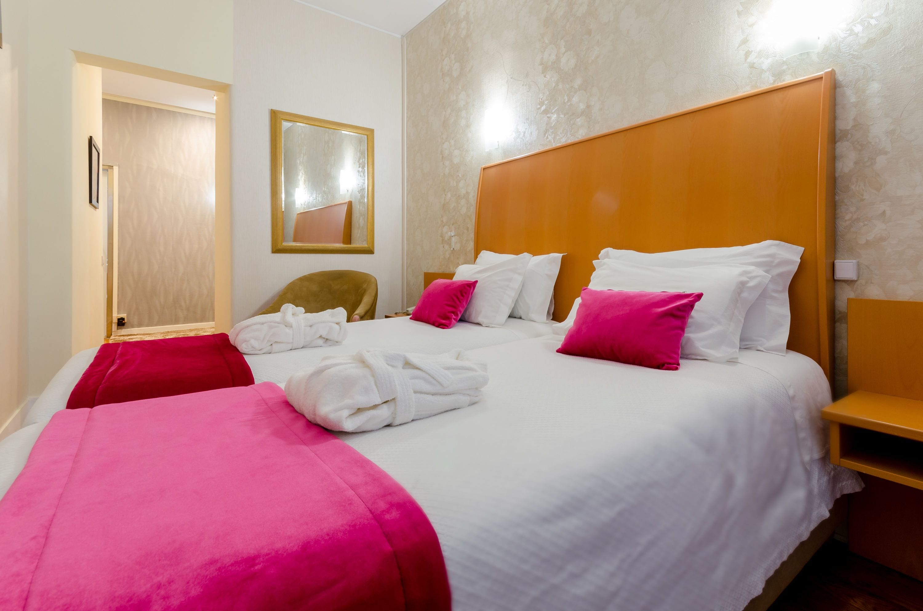 A hotel room with a large bed, two bedside tables, a chair, and a mirror on the wall.