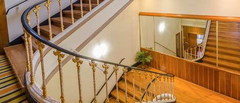 A wooden staircase with ornate golden railings and a mirrored wall.