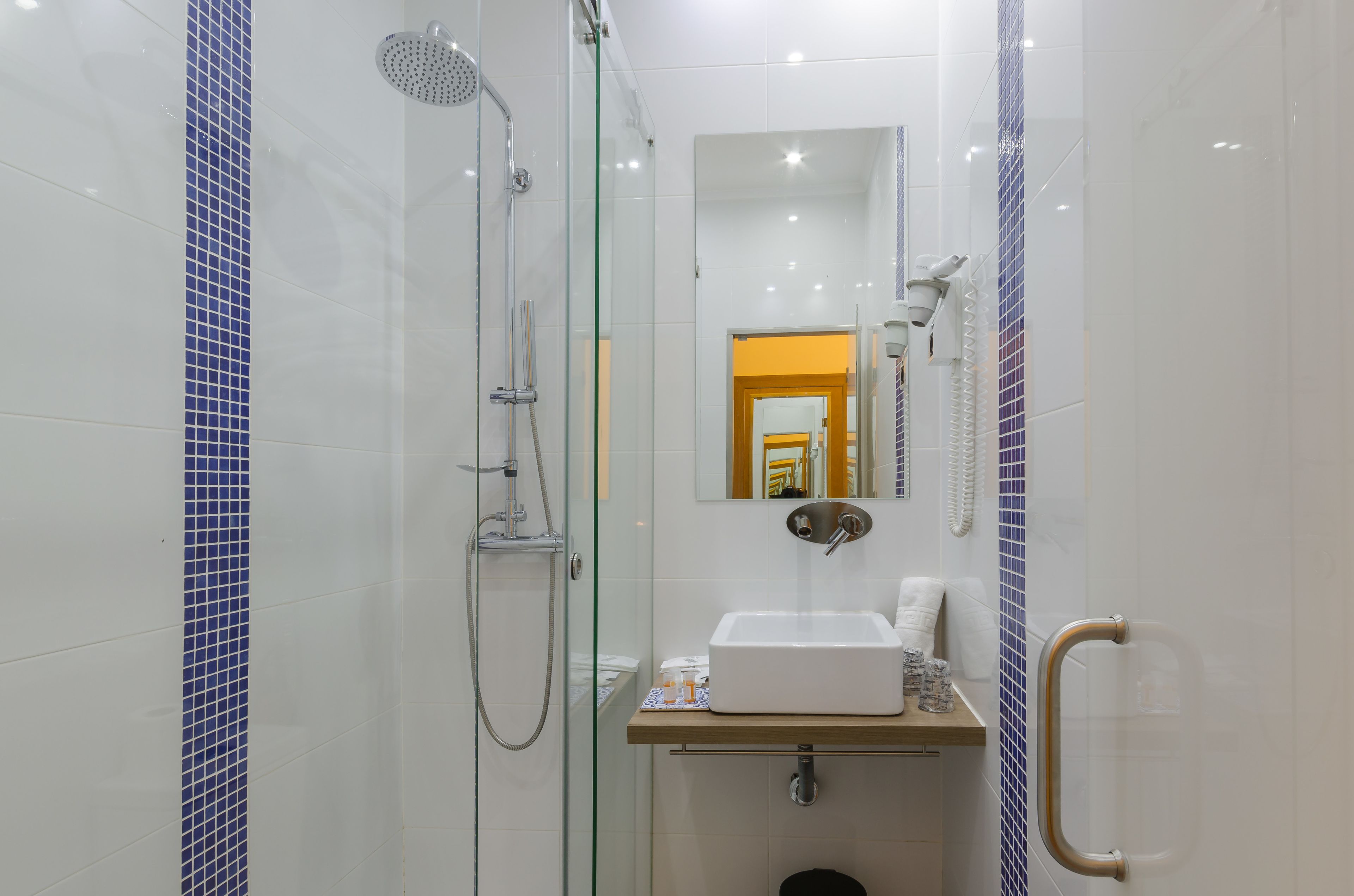 A modern bathroom with a glass-enclosed shower, a white sink, and a mirror above it.