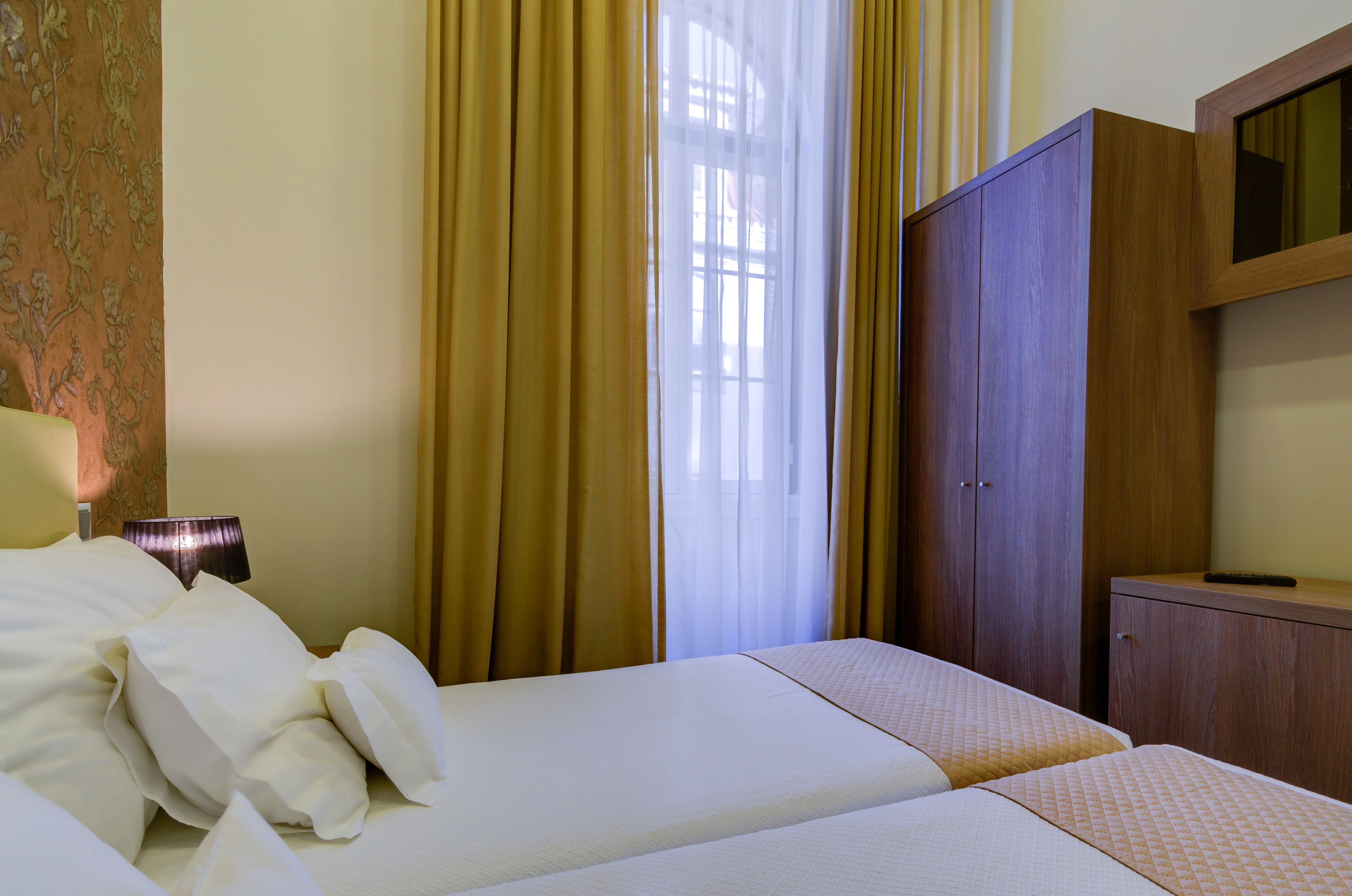 Une chambre d’hôtel avec deux lits, une armoire et une lampe.