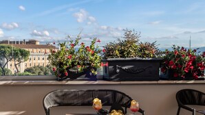 Una terraza con mobiliario exterior, una mesa con comida y bebidas, y plantas en macetas.