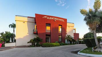 The exterior of Albatros Hotel with a modern design, featuring a red facade and a clear sky.