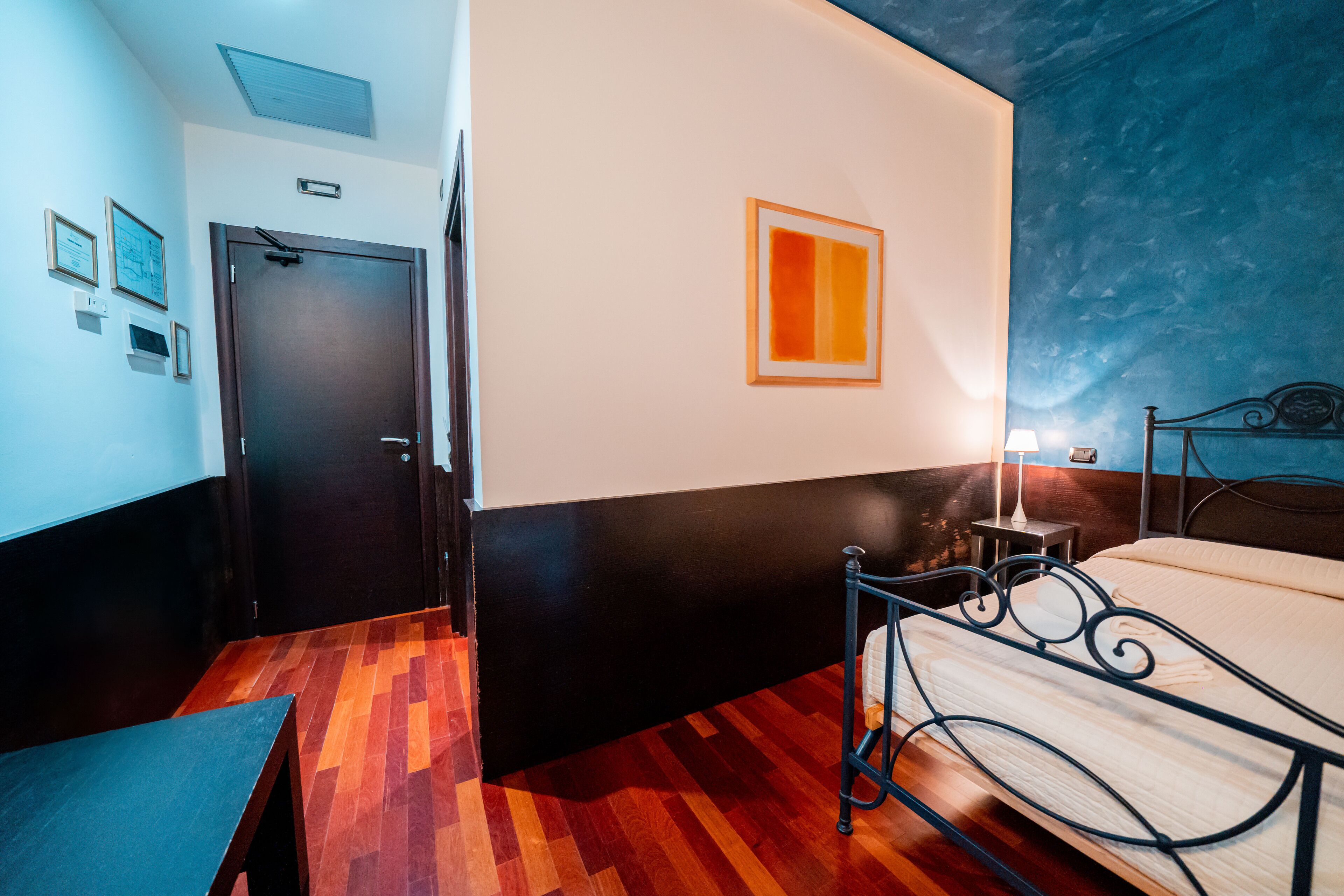 Ein Hotelzimmer mit Bett, Nachttisch, Wandlampe und Tür.