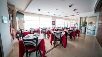 Un comedor con varias mesas y sillas, cada una cubierta con un mantel rojo.