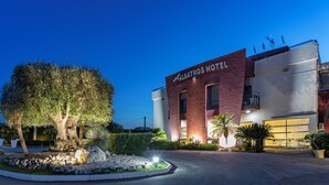 El exterior del Hotel Albatros, con un diseño moderno, presenta un letrero destacado, una entrada bien iluminada y jardines cuidados.