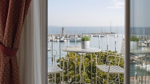 A balcony with a white table and two chairs, overlooking a marina with boats and a lighthouse. - Hotel Mayer & Splendid – Wellness e Spa (Desenzano del Garda)