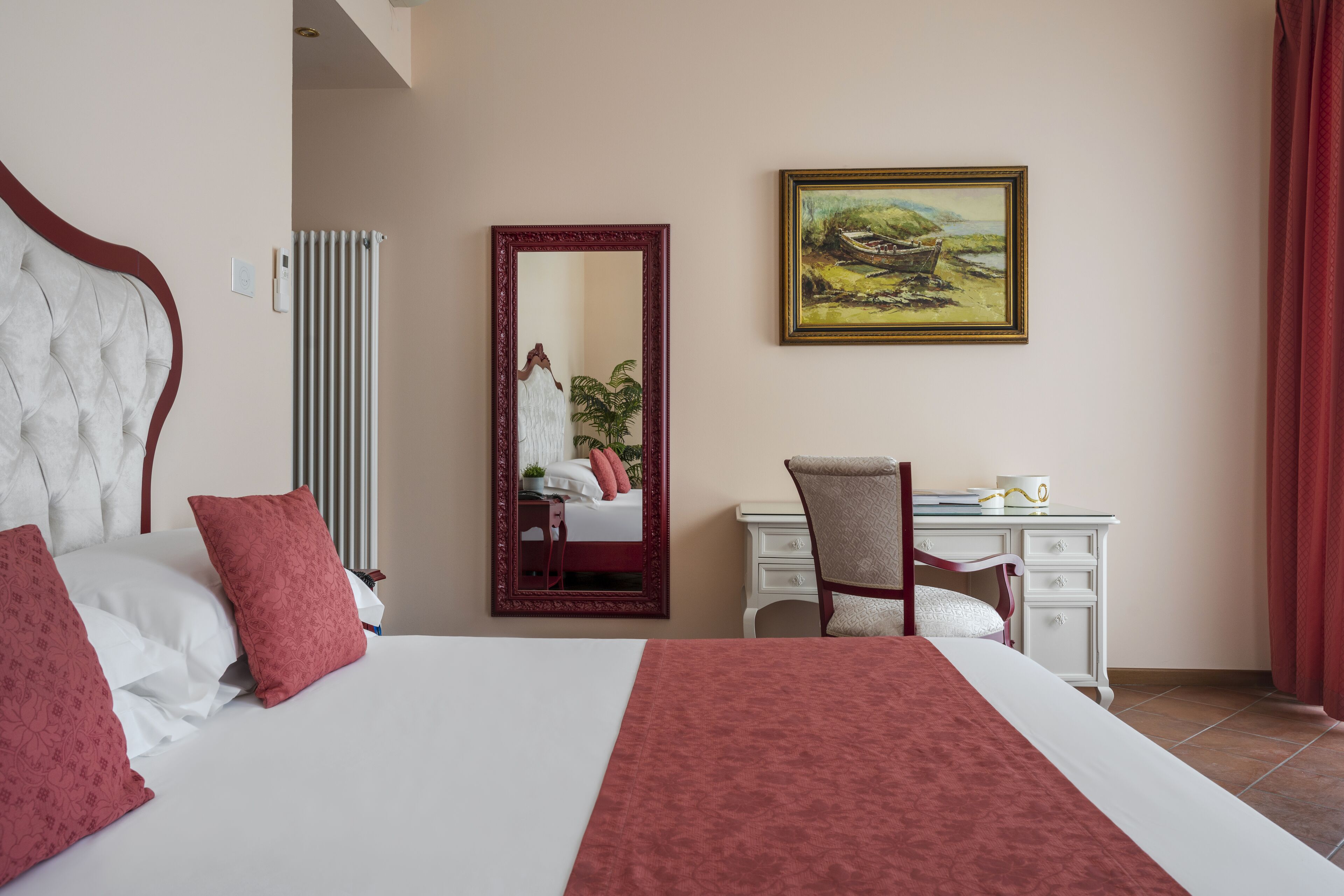 Habitación de hotel con una cama grande, un escritorio, una silla, un espejo y un cuadro en la pared.