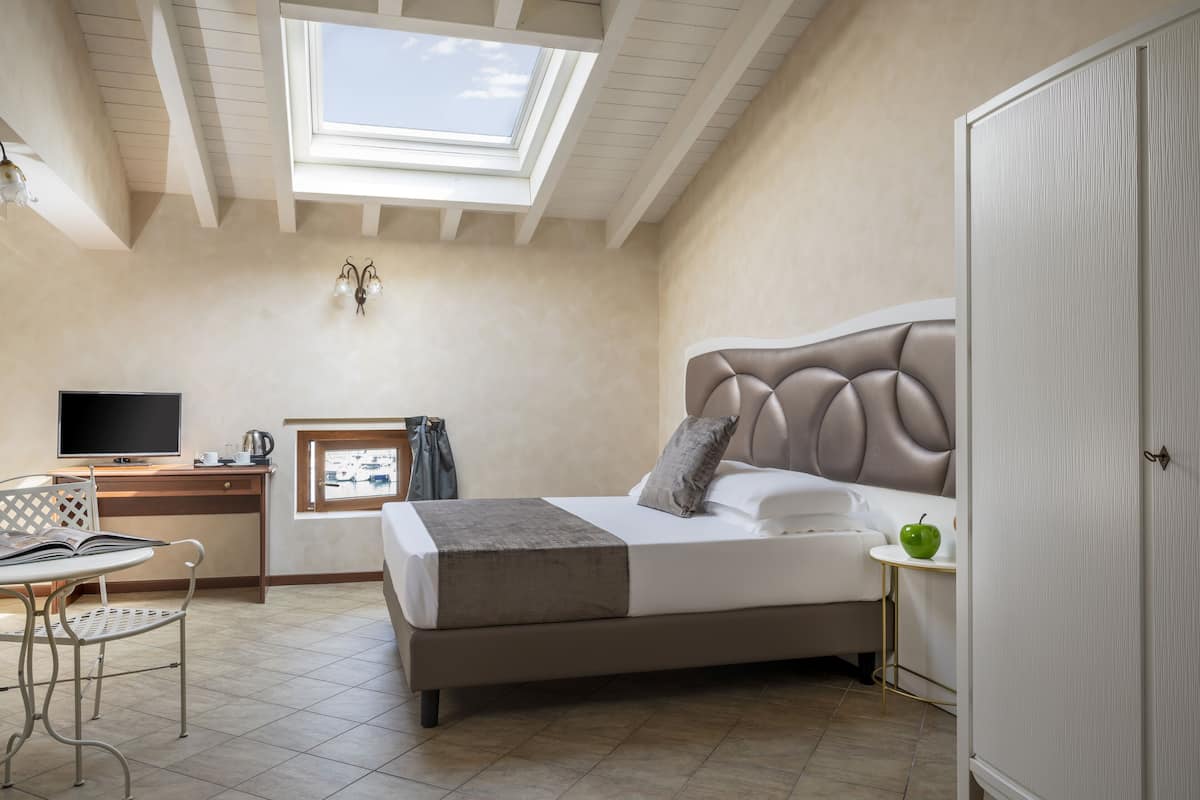 Ein Schlafzimmer mit einem Bett, einem Schreibtisch, einem Stuhl, einem Fernseher und einem Dachfenster.