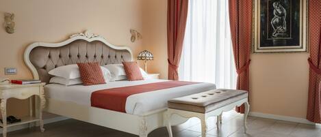 A bedroom with a large bed, a bedside table, a nightstand, and a wall-mounted lamp.