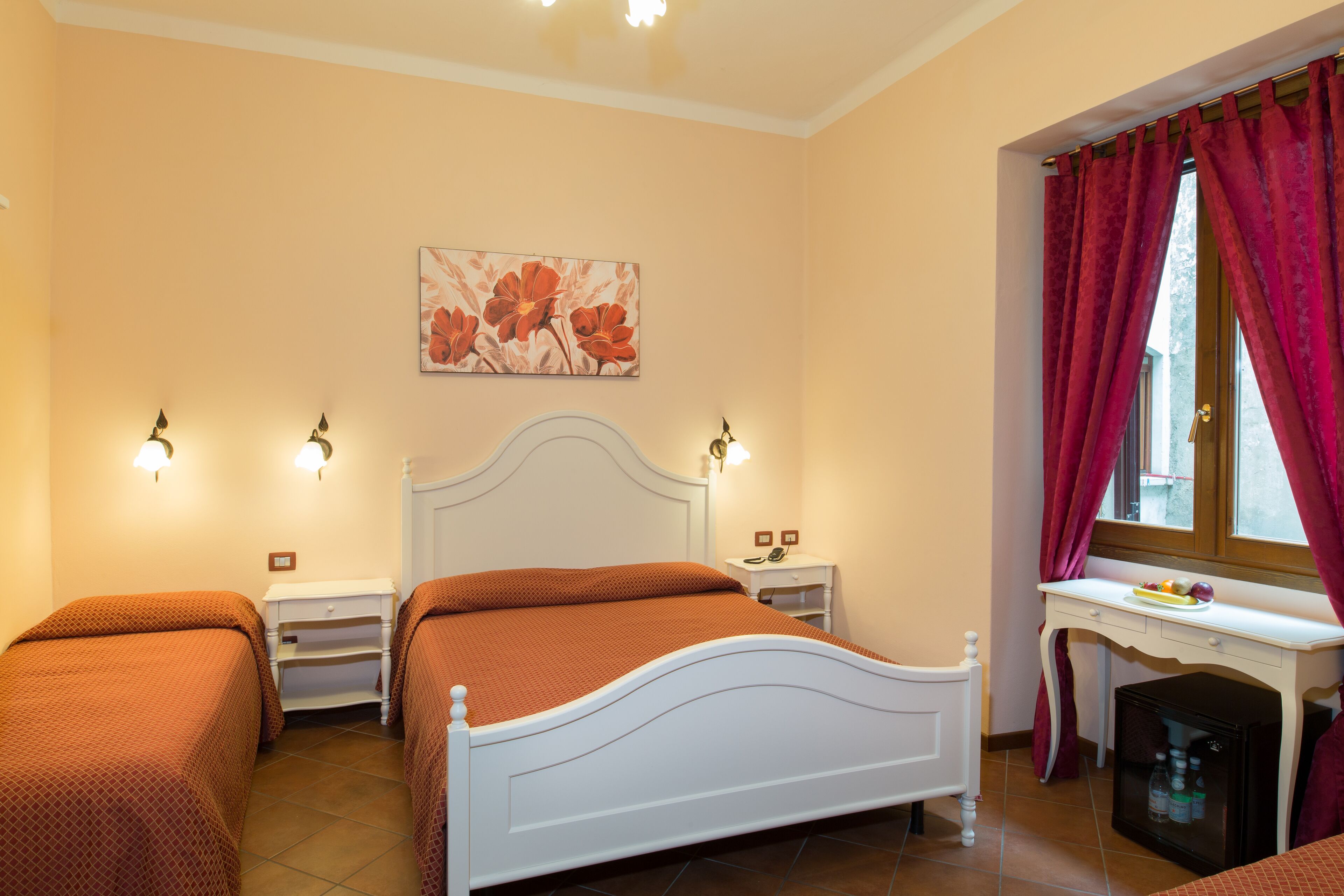 Camera da letto con due letti, una scrivania e un piccolo armadietto.