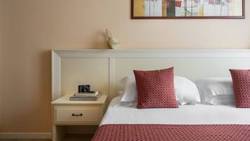 Une chambre d’hôtel avec un lit, une table de chevet, un appareil photo et un tableau encadré au mur.