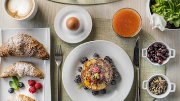 A breakfast setting with croissants, pancakes, berries, and a coffee cup.