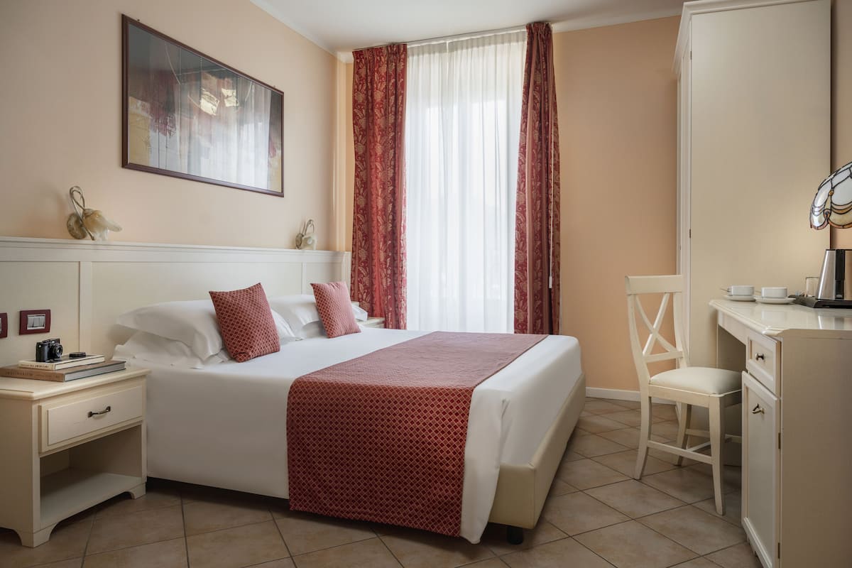 Ein ordentlich eingerichtetes Schlafzimmer mit Bett, Nachttisch, Stuhl und Schreibtisch mit Stuhl.
