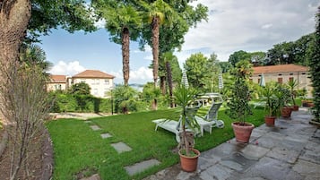 Un jardin bien entretenu, avec une pelouse, des plantes en pot et du mobilier d’extérieur.