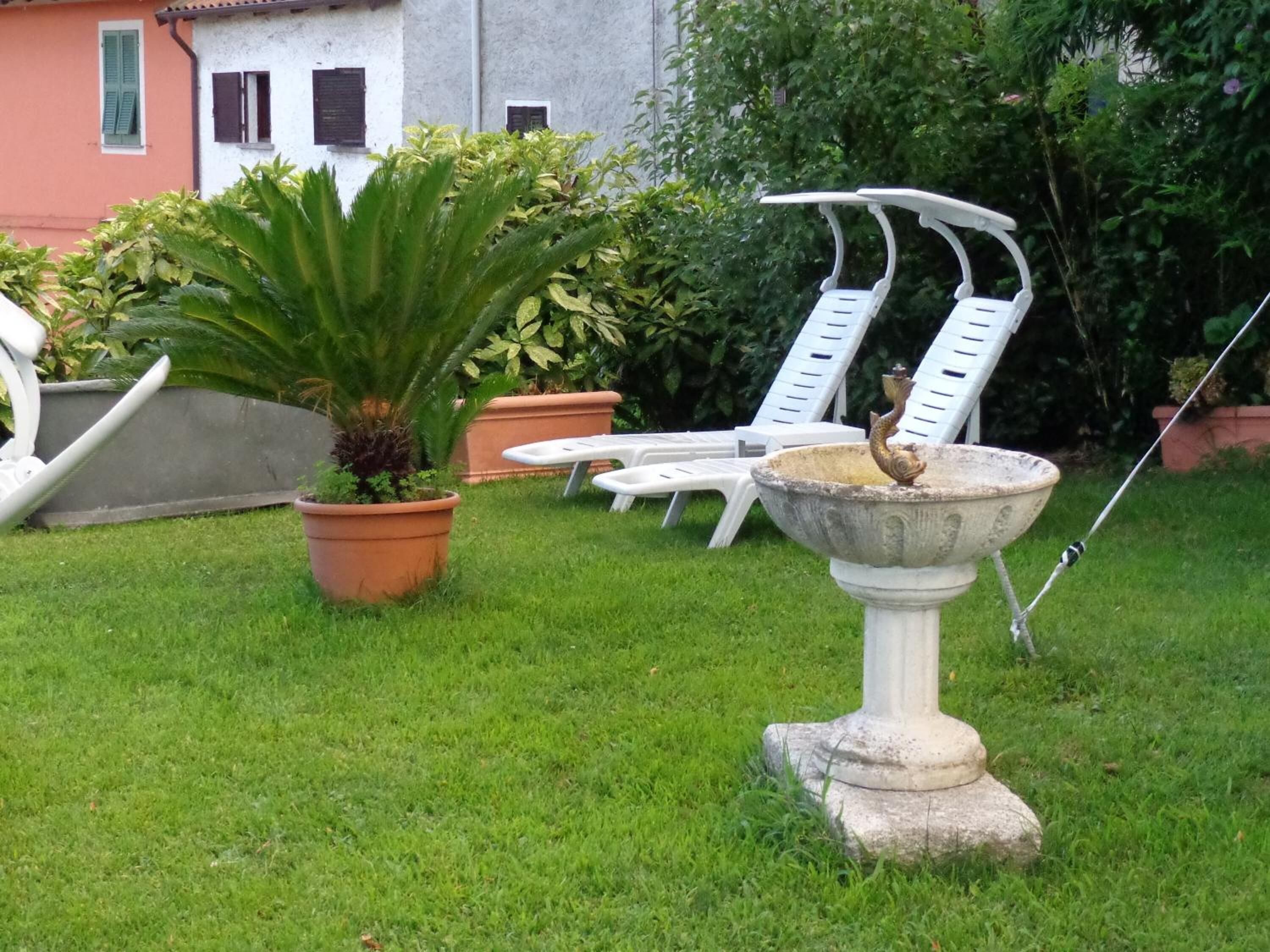 A garden with a fountain, potted plants, and outdoor furniture.