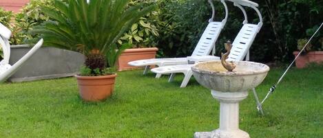 A garden with a fountain, potted plants, and outdoor furniture.