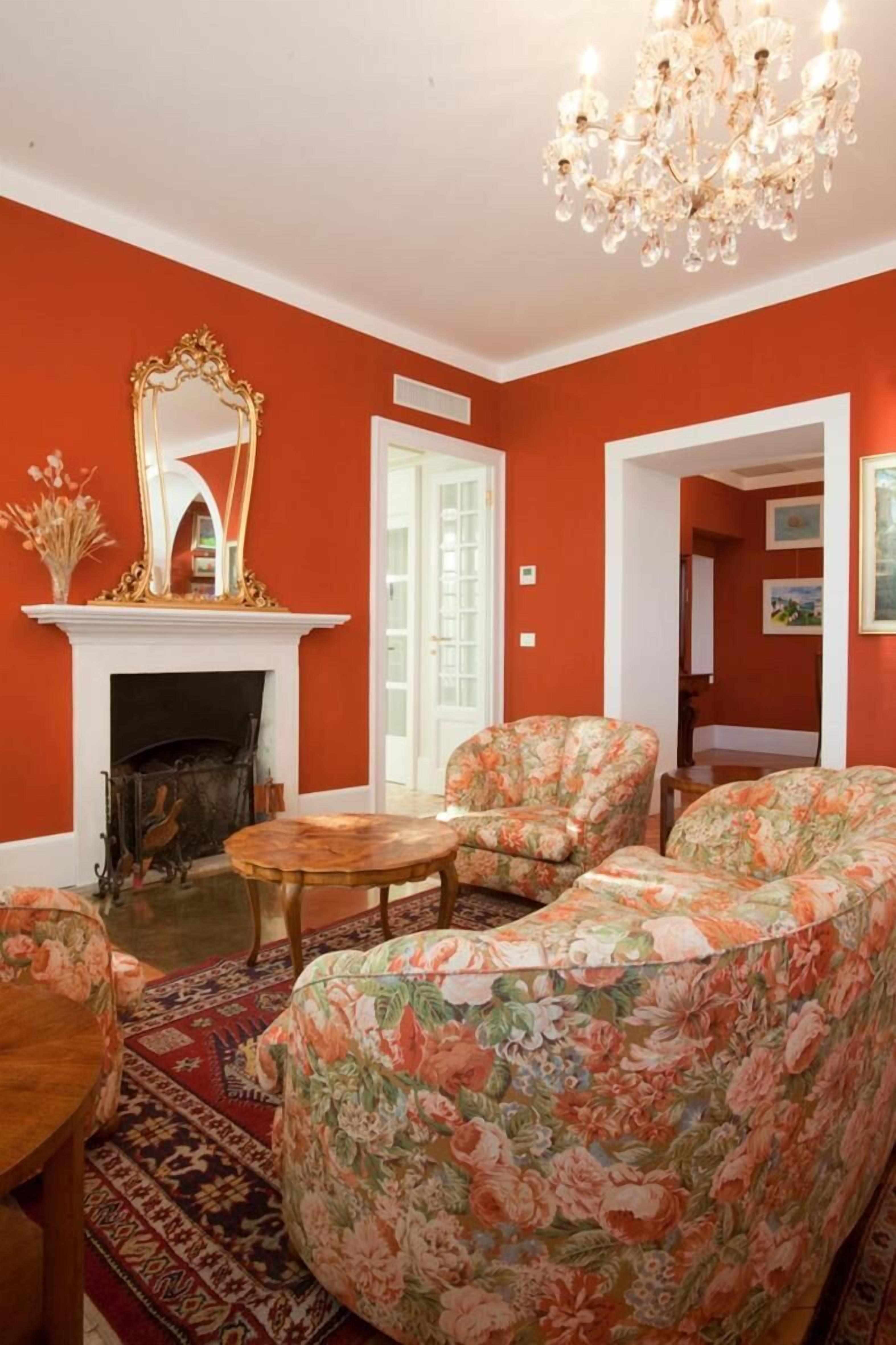 A living room with a fireplace, floral-patterned sofa, and a chandelier.