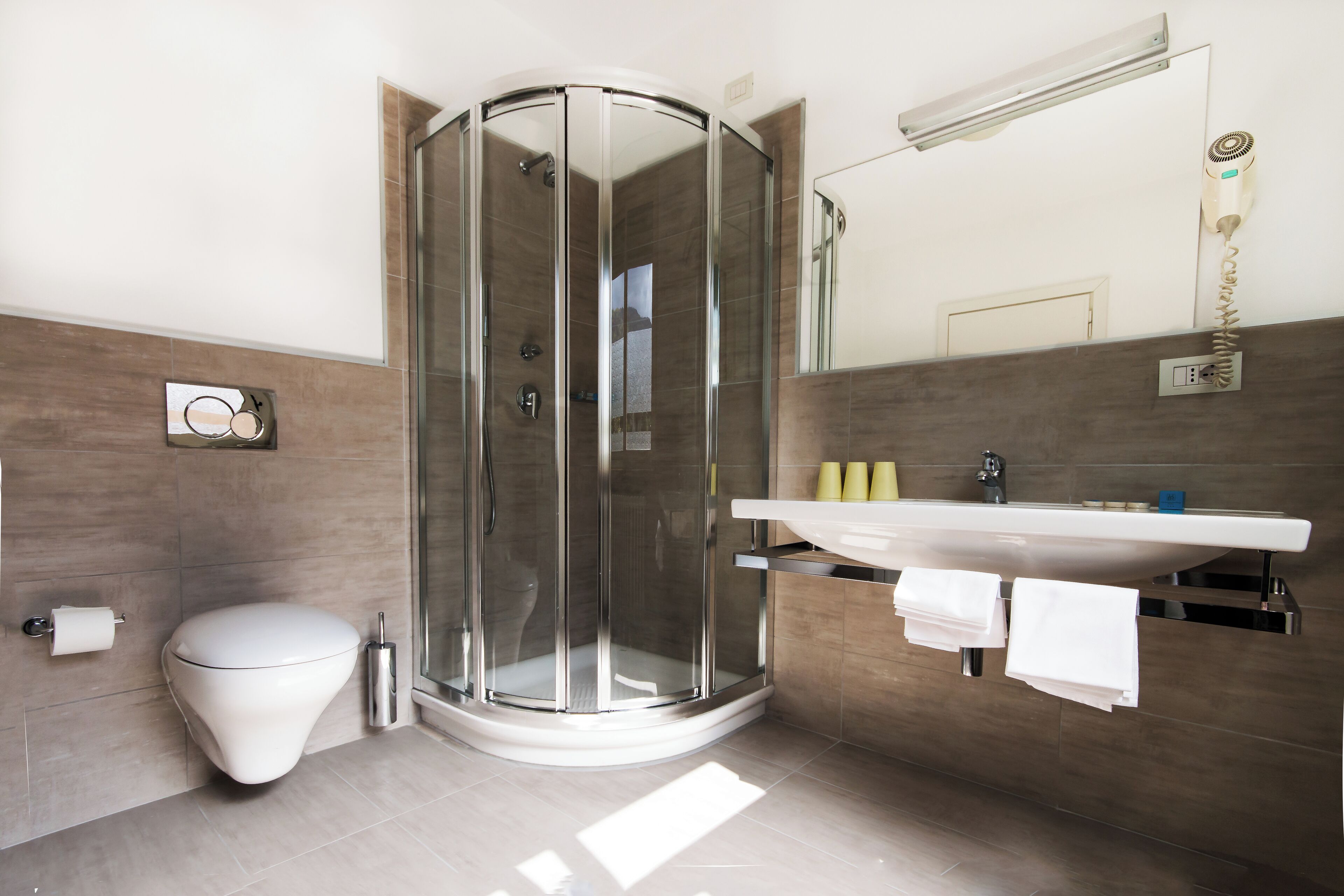 A modern bathroom with a glass-enclosed shower, a white toilet, and a sink with a mirror above it.