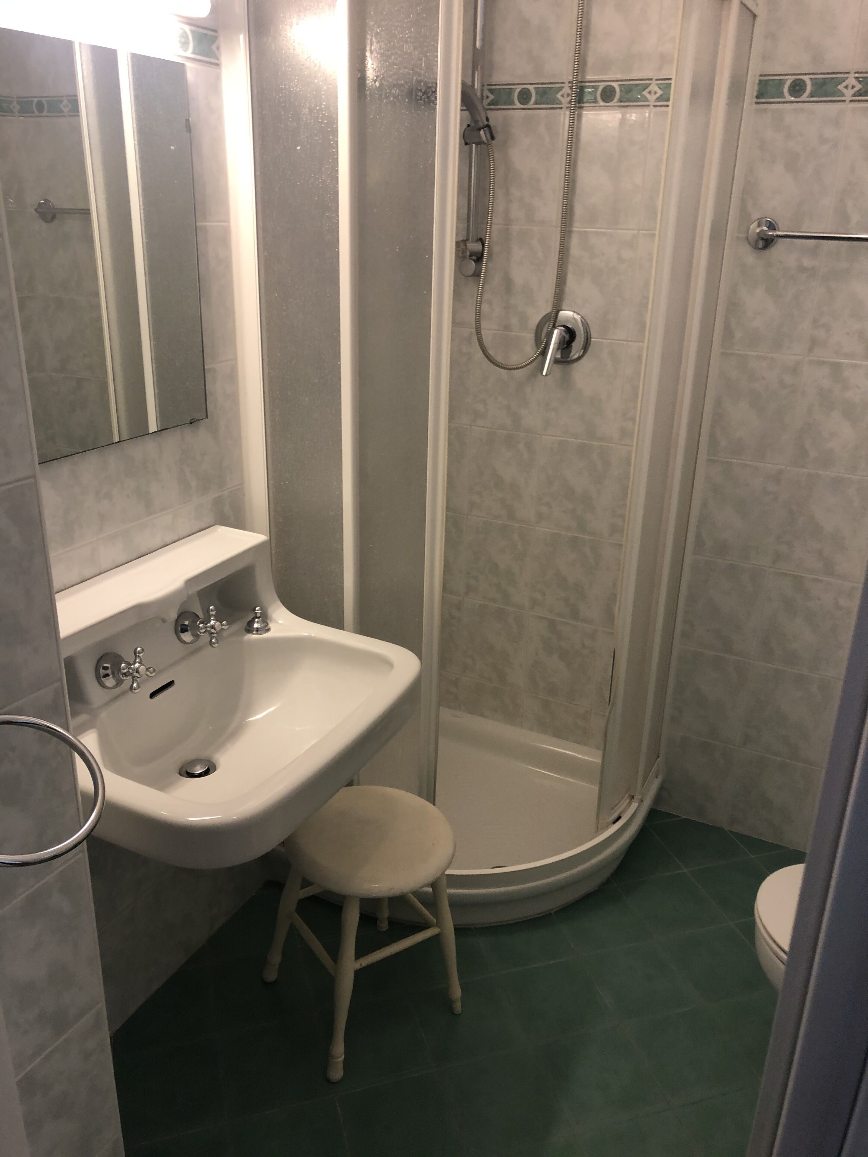 Et badeværelse med et væghængt håndvask, en bruseniche og et toilet.