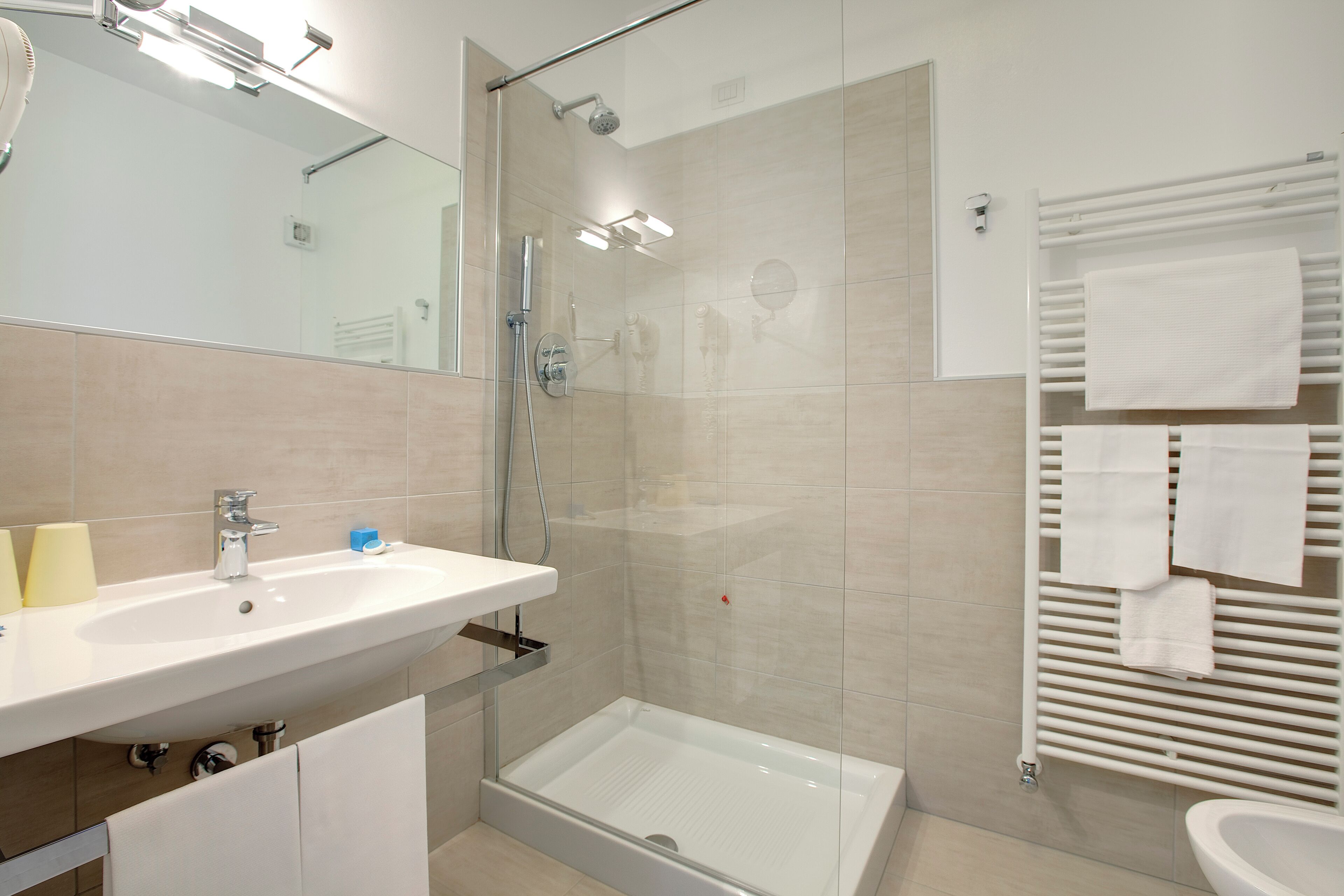 Een moderne badkamer met een wastafel, spiegel, douche en handdoekhouder.