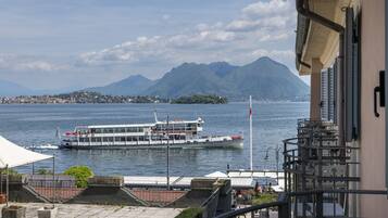 A view of a river with a boat, a mountainous landscape, and a building with a balcony.