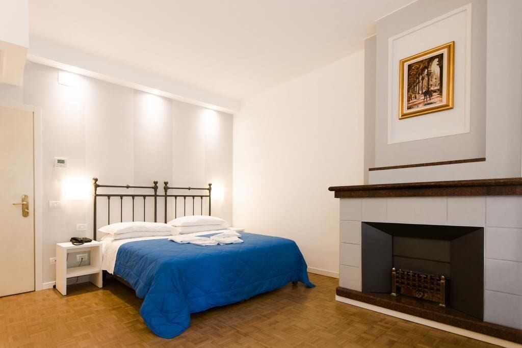 Une chambre à coucher avec un lit, une table de chevet et une cheminée.