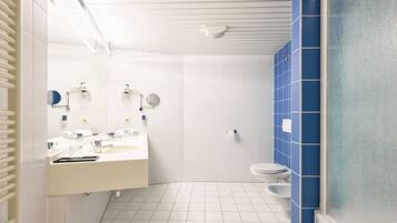 Une salle de bain avec un lavabo blanc, un miroir et des toilettes, et des murs recouverts de carreaux bleus.