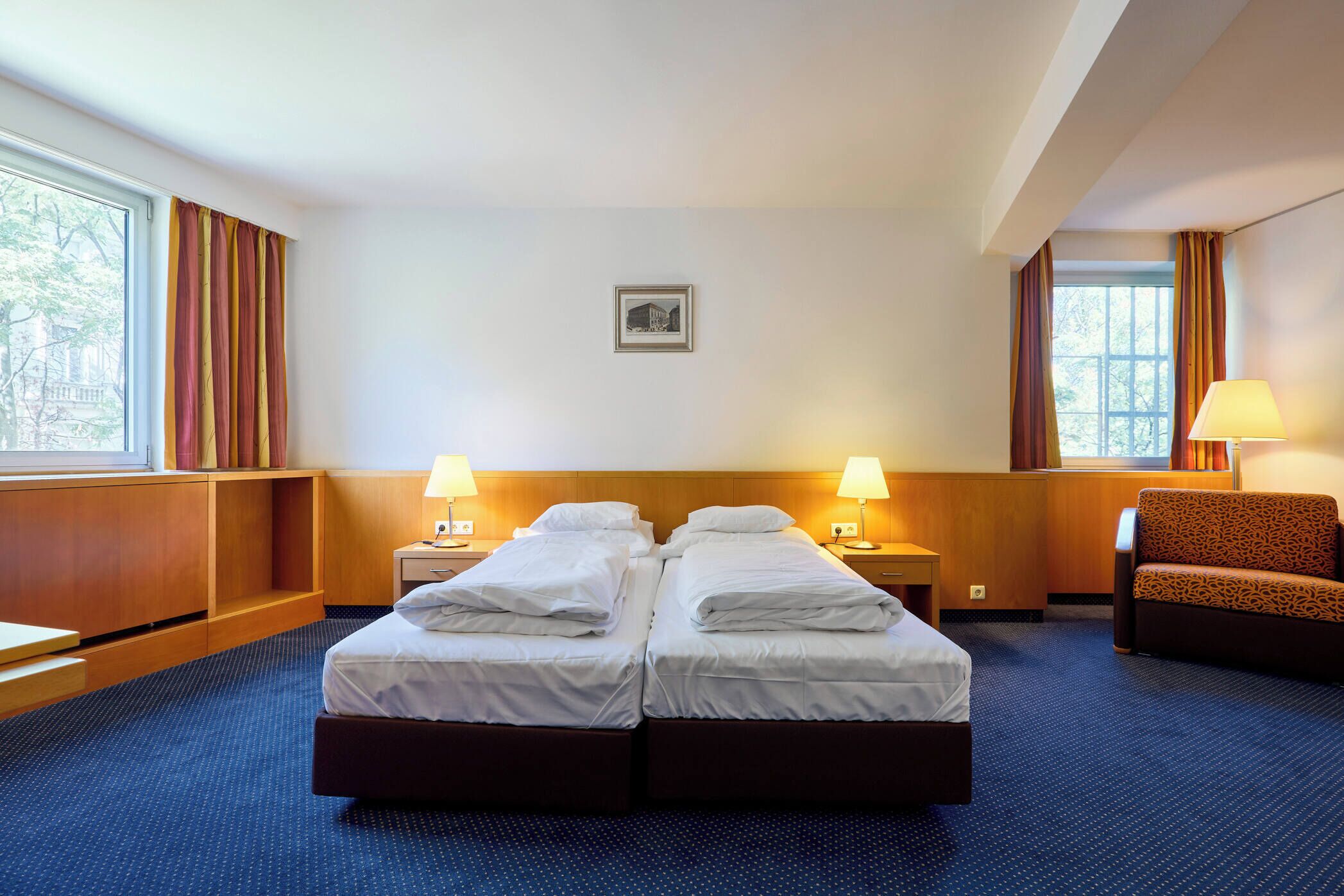 Ein Hotelzimmer mit zwei Betten, einem Schreibtisch, einem Stuhl und zwei Lampen.