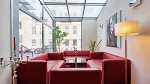 A modern interior with a glass ceiling, red leather sofas, a central coffee table, and a floor lamp. - Hotel Strudlhof (Vienna)