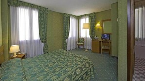 A hotel room with a bed, two chairs, a desk with a lamp, and a television. - Hotel Nazionale (Venice)