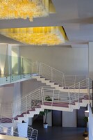 Un interno moderno con scala dotata di ringhiera in vetro, un design di soffitto originale e piante in vaso.