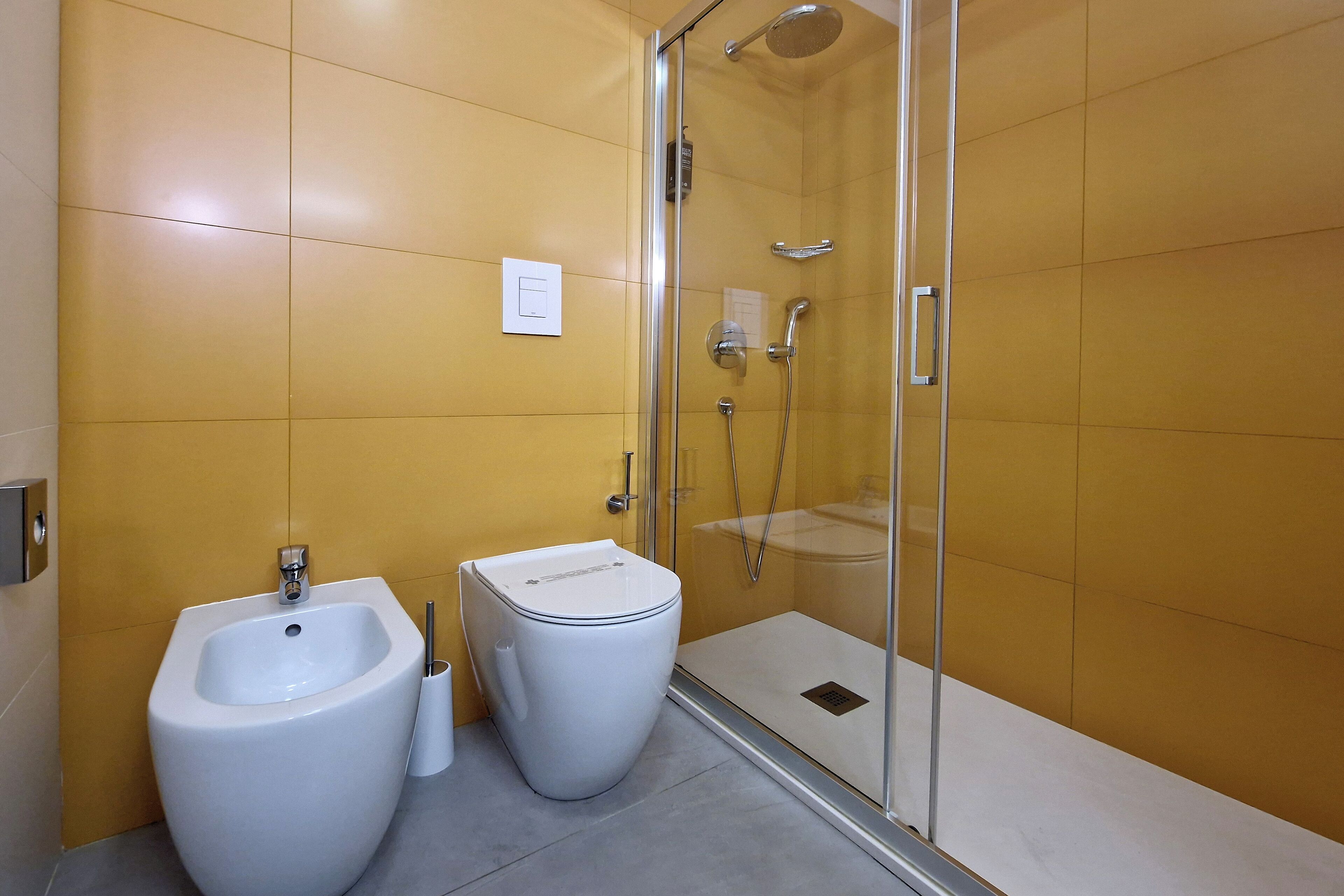 Un baño moderno con bidé, inodoro y ducha de vidrio.