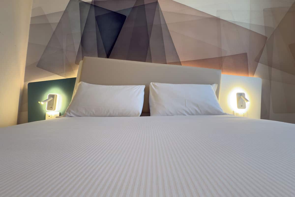 A bed with a white headboard and two bedside lamps.