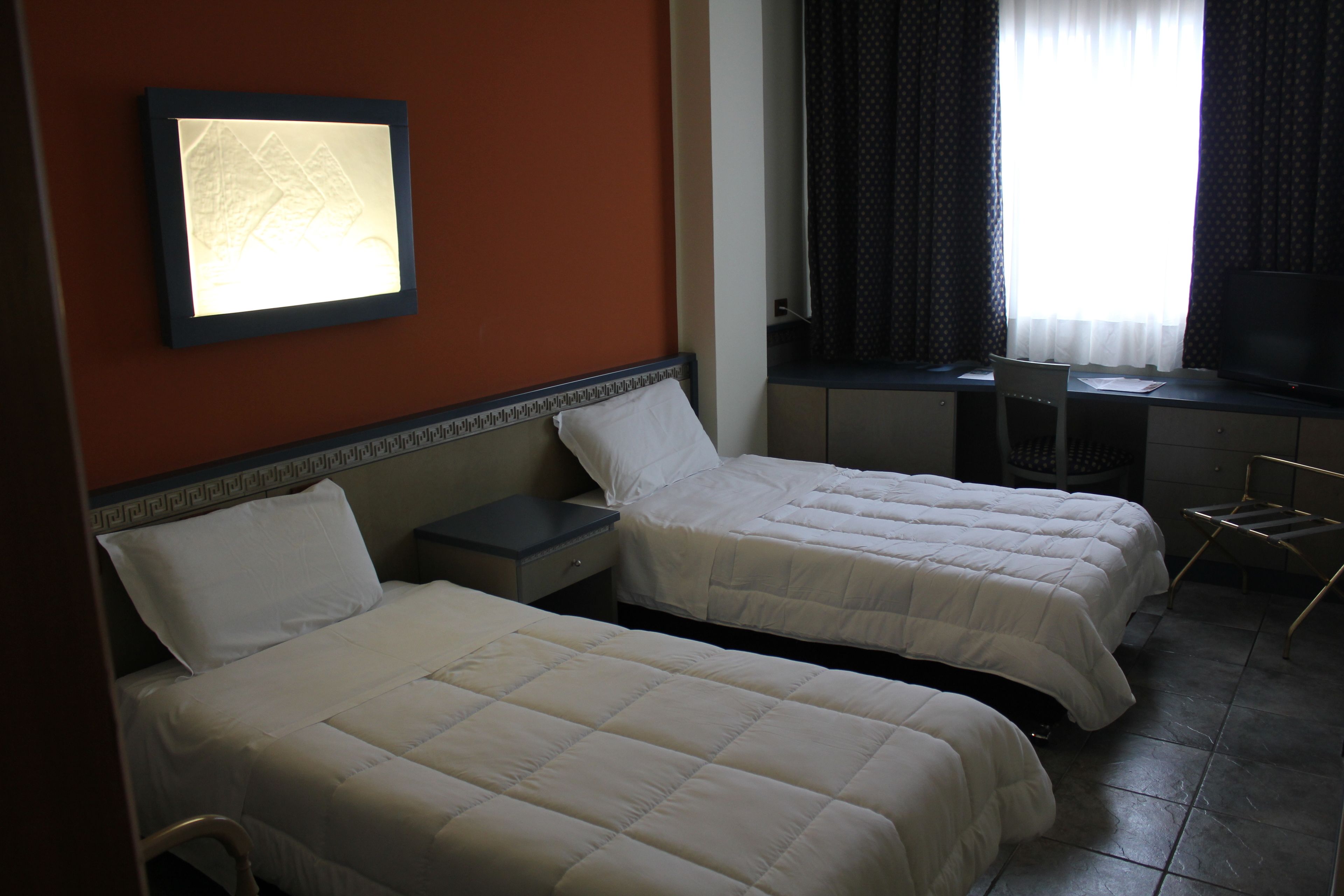 Una habitación de hotel con dos camas, un escritorio, una silla y un televisor.