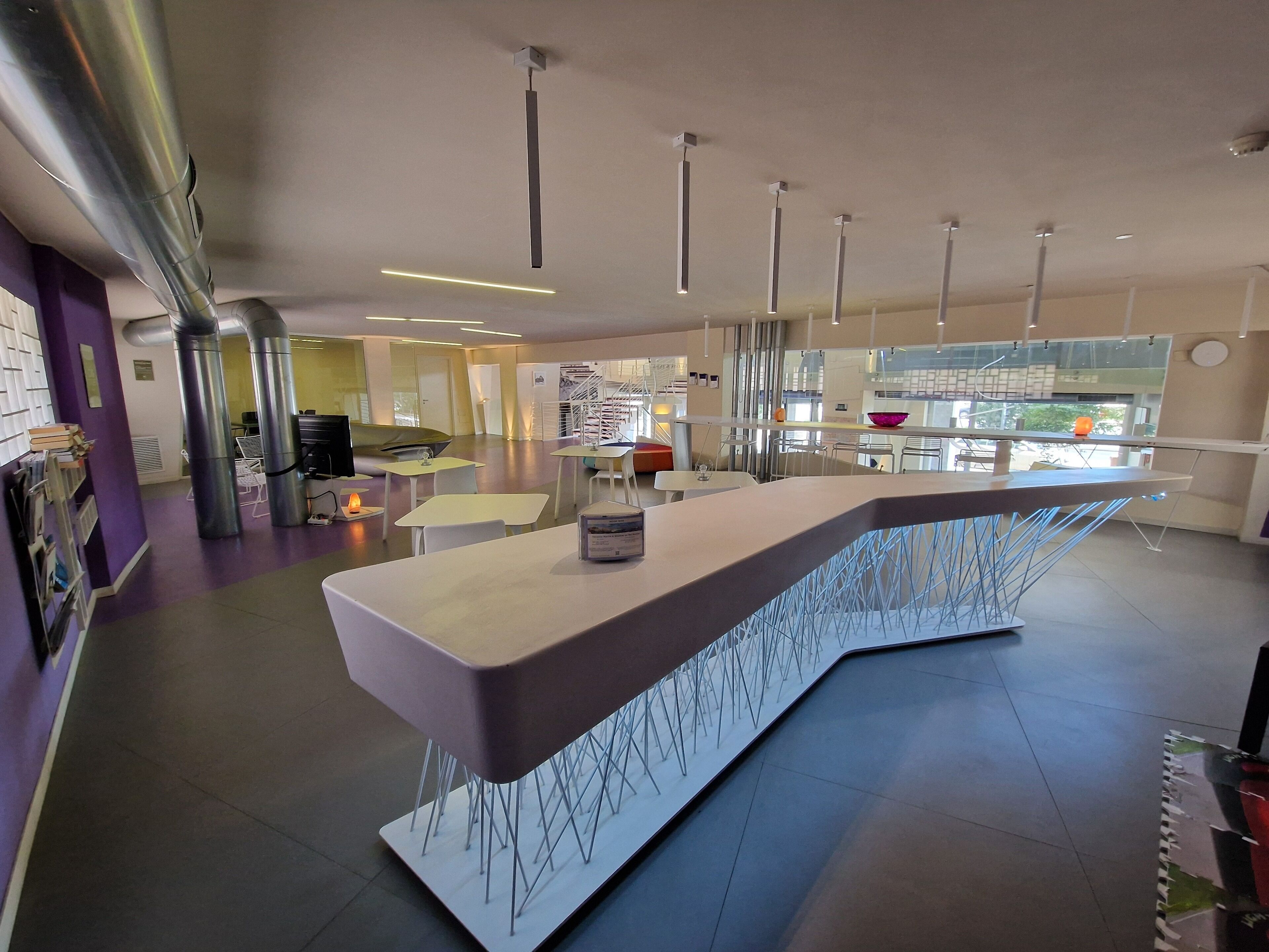 Un interior moderno con una barra central, diferentes disposiciones de asientos y una cocina a la vista.