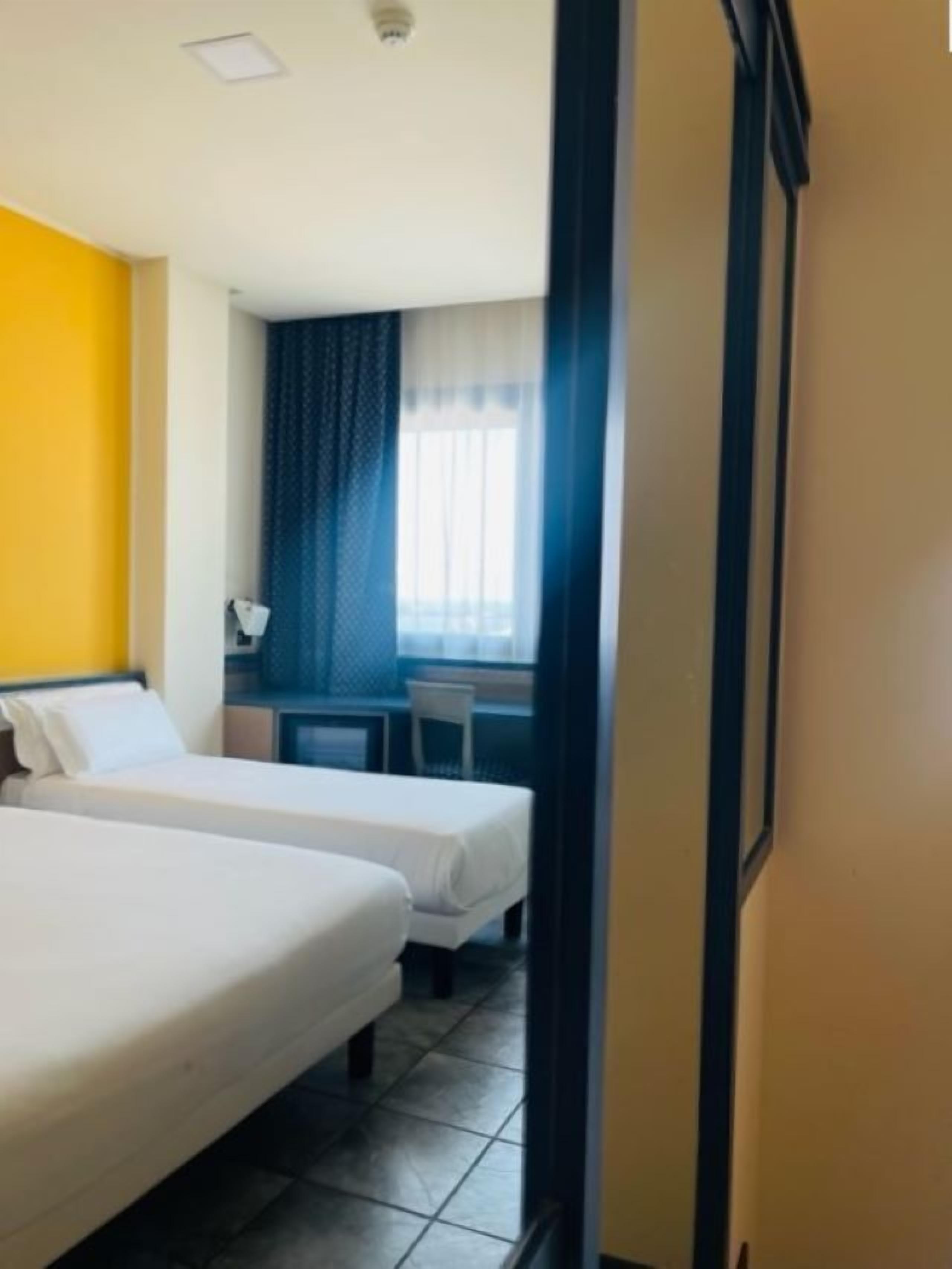 Een hotelkamer met twee bedden, een bureau en een stoel.