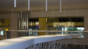 A modern bar area with a curved counter, white chairs, and a glass partition.