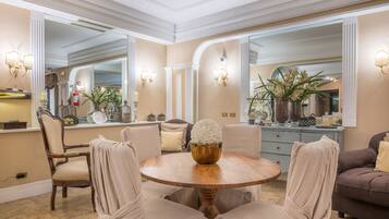 A dining area with a round wooden table, beige upholstered chairs, and a decorative centerpiece.