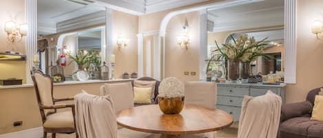 A dining area with a round wooden table, beige upholstered chairs, and a decorative centerpiece.