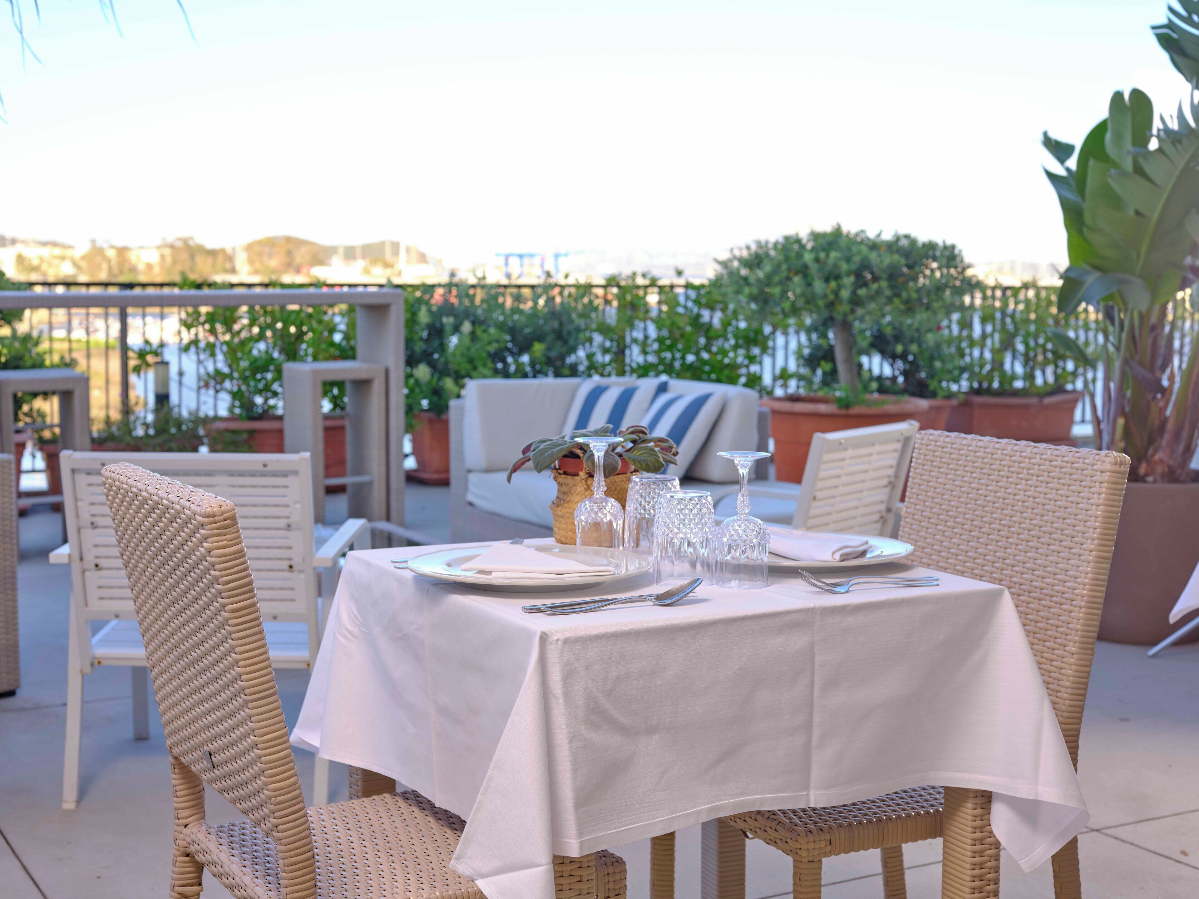 An outdoor dining area with wicker chairs and a table set for two.