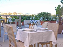 Un espacio de comedor al aire libre con sillas de mimbre y una mesa dispuesta para dos personas.