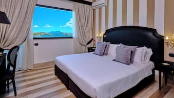 Camera d'albergo con un letto grande, una scrivania, una sedia, un condizionatore e vista su un corpo d'acqua.