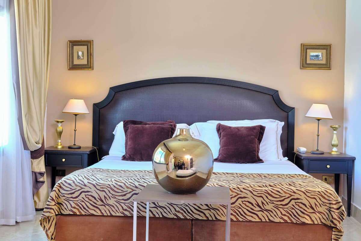 A hotel room with a large bed, two bedside tables, a mirror, and a decorative vase.