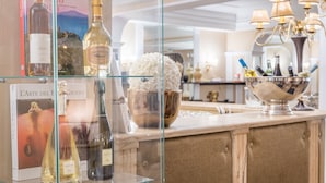 A bar area with a glass display case containing various bottles of alcohol, a bowl of decorative items, and a book titled 'L'arte del Giusto'.