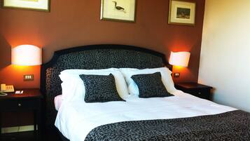 A hotel room with a bed, two nightstands, and three framed pictures on the wall.