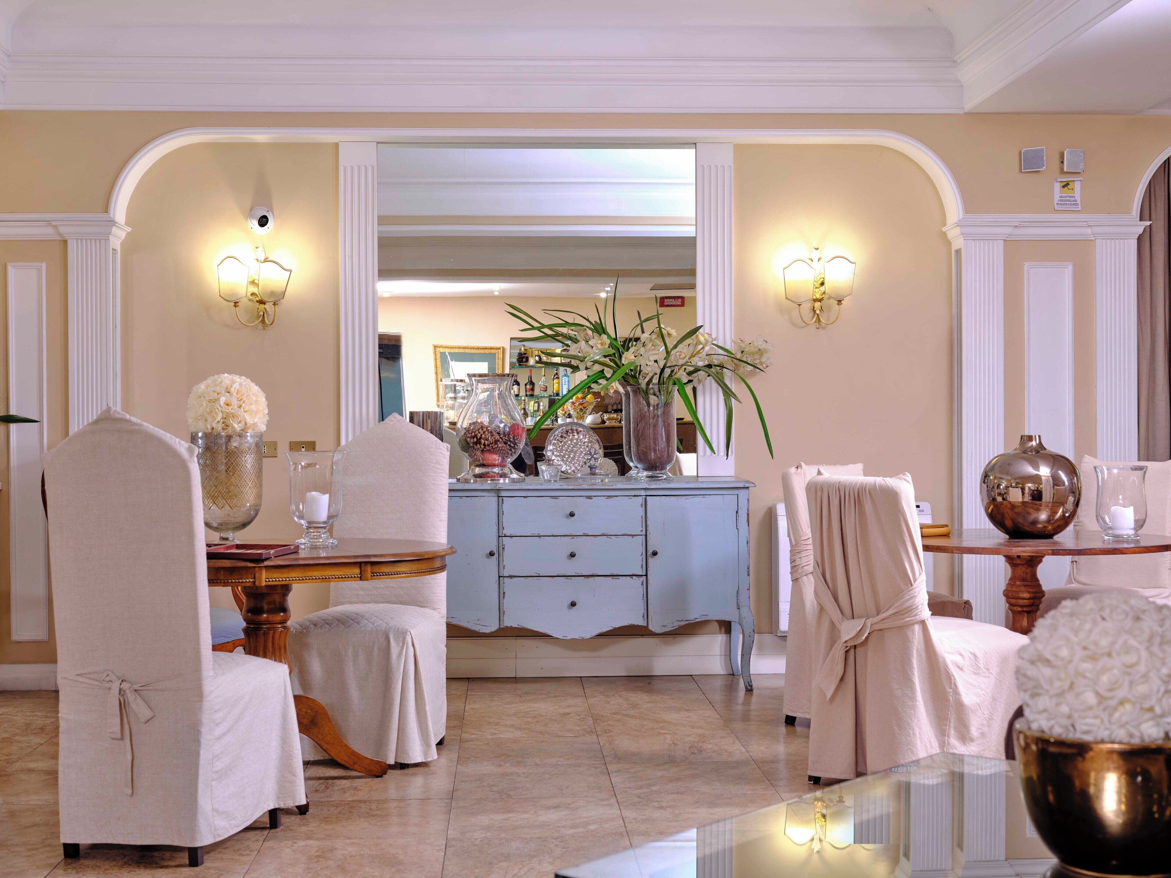A well-lit, elegantly furnished dining area with a central island, chairs, and a decorative vase.