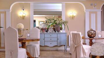 Un comedor bien iluminado y elegantemente decorado, con una isla central, sillas y un jarrón ornamental.