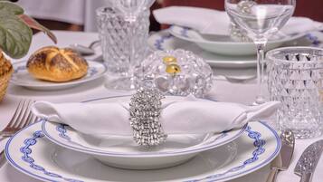 Mesa formal dispuesta para comer, con platos blancos, vajilla de borde azul, cristalería y cubiertos.