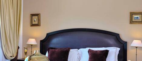 A hotel room with a large bed, two bedside lamps, a decorative vase, and a zebra-patterned throw.