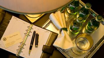 Ein Hotelzimmer mit einem Planer, Stiften, einem Glas und Flaschen Perrier-Wasser auf einem Tablett.
